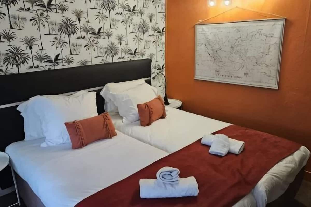A hotel room with two beds, a map on the wall, and a red blanket on the bed.