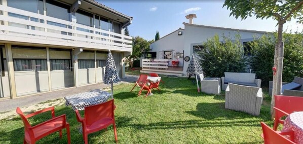 Un patio con mobiliario exterior, una pequeña mesa y un árbol ornamental.