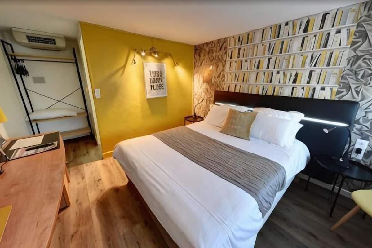 A bedroom with a bed, bedside tables, a desk, and a bookshelf.