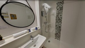 Casa de banho com lavatório, espelho e chuveiro.