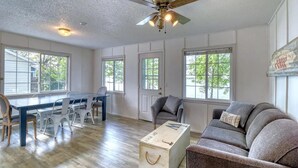A spacious room with a dining table, chairs, a sofa, and a ceiling fan.