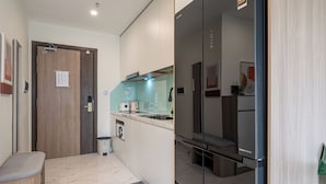 A compact kitchen with a built-in oven, a small sink, and a countertop with a kettle.