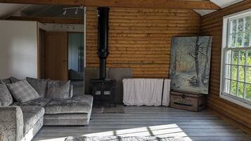 Un interior d'una cabana acollidora, amb decoració de fusta, una llar de foc, un sofà i un quadre a la paret.