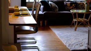 A dining area with a wooden table set for four, a sofa, and a small round table with a vase. - Judie's garden in Schaalby (Schaalby)