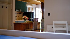 A cozy kitchen with wooden cabinets, a black refrigerator, and a dining area with a chair and table. - Judie's garden in Schaalby (Schaalby)