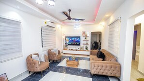 A modern living room with a flat-screen TV, two sofas, a coffee table, and a ceiling fan.