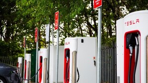 Una fila de estaciones de carga para vehículos eléctricos Tesla, con un automóvil estacionado al frente.