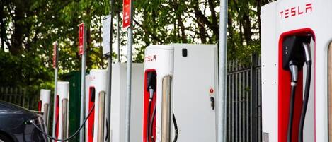 A row of Tesla electric vehicle charging stations with a car parked in front.