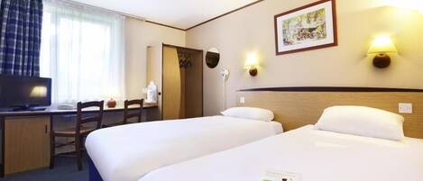 A hotel room with two beds, a desk with a chair, a television, and a window with curtains.