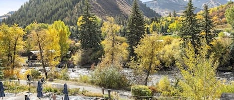 A mountainous landscape with autumn foliage, outdoor seating, and a view of a river.