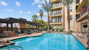 A swimming pool with lounge chairs, palm trees, and a multi-story building with balconies. - Boulevard Stays Modern Roosevelt Row Suite 2BR Pool, Gym 5 (Phoenix)