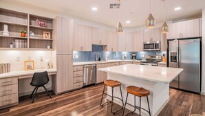 A modern kitchen with a central island, bar stools, a microwave, and a refrigerator. - Boulevard Stays Modern Roosevelt Row Suite 2BR Pool, Gym 5 (Phoenix)