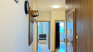 Un passadís amb un radiador, obra d'art emmarcada, un rellotge i una porta de fusta.