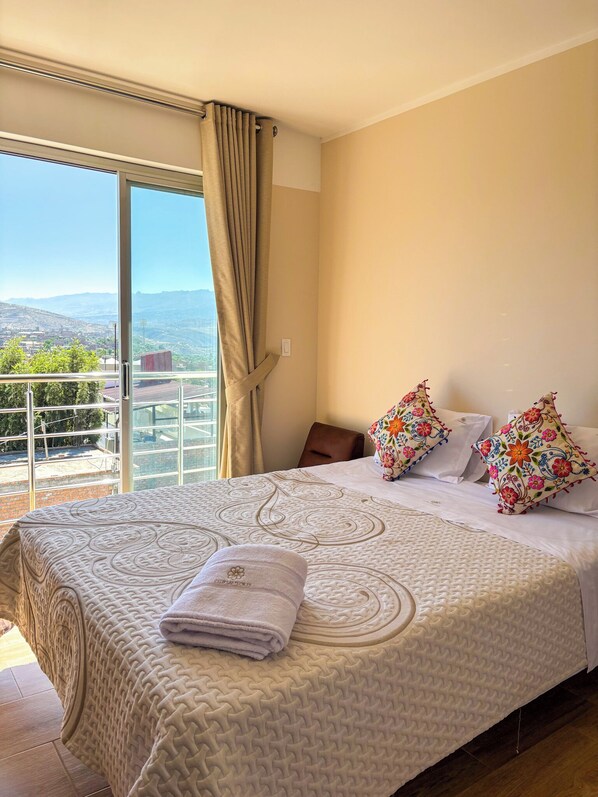 Une chambre d’hôtel avec un grand lit, une vue sur la ville et un balcon.