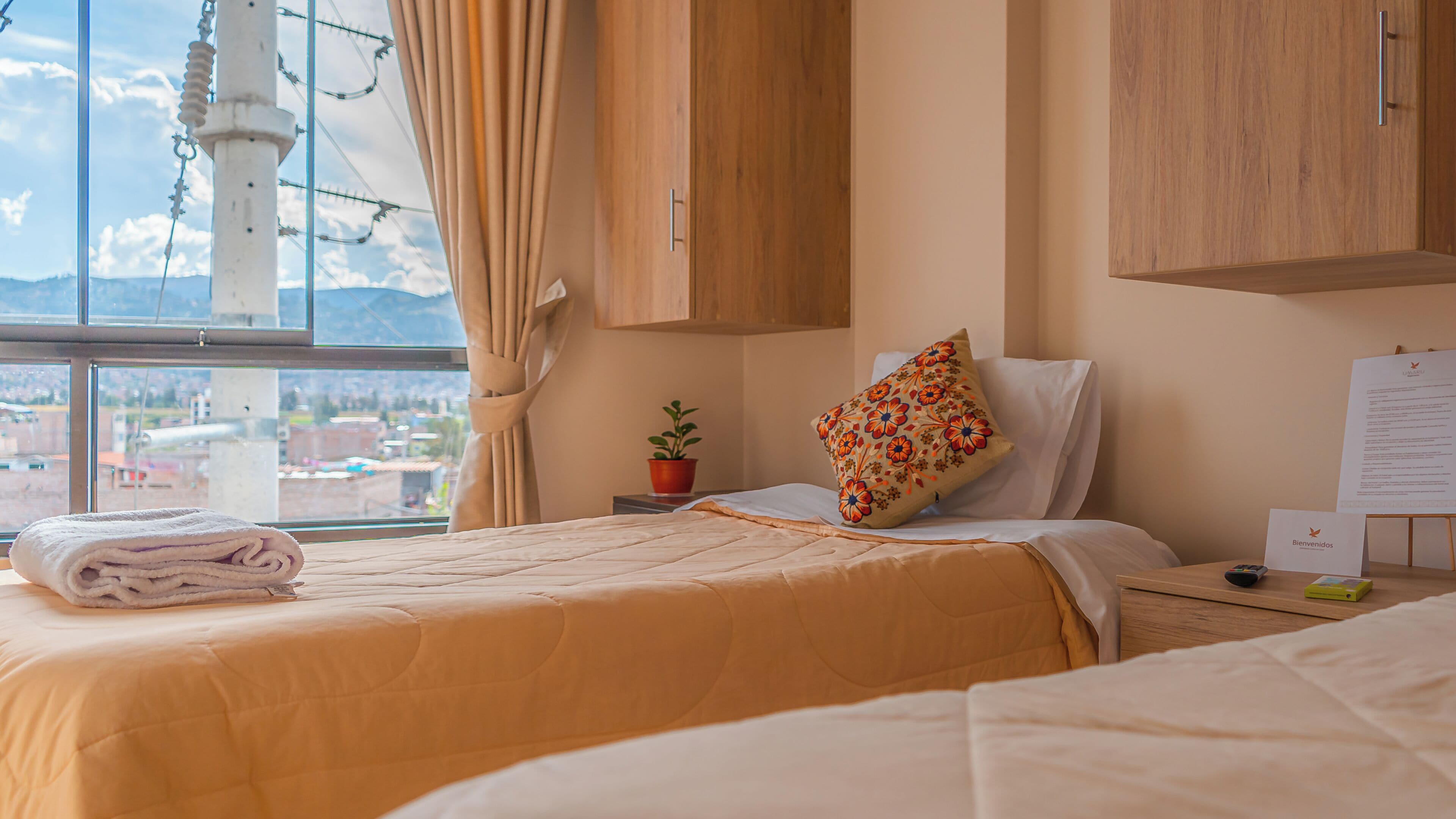 A hotel room with a bed, a nightstand, a window with a view, and a wooden cabinet.