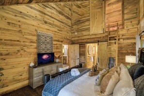 A wooden cabin bedroom with a bed, dresser, and a wall-mounted TV. - Whimsical Ways - Hot tub-screen porch-pet friendly (Blue Ridge)