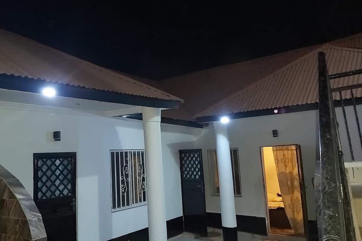 Un edificio con un patio techado, varias puertas con rejas metálicas y un extintor cerca de la entrada.