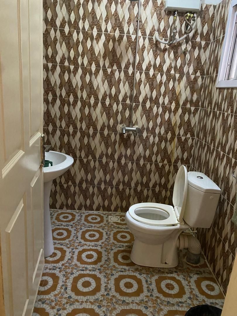 A bathroom with patterned tiles, a toilet, a sink, and a shower area.