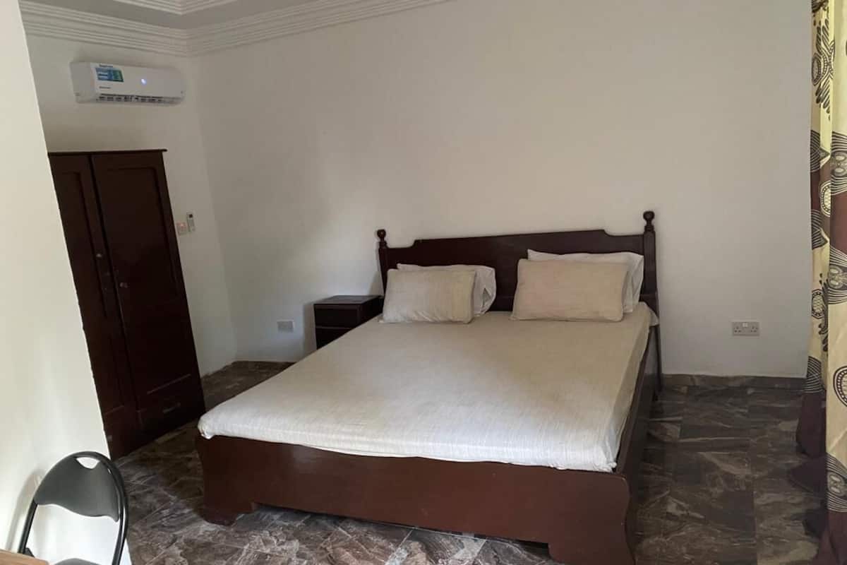Un dormitorio con una cama grande, un armario de madera, una mesita de noche y una silla.
