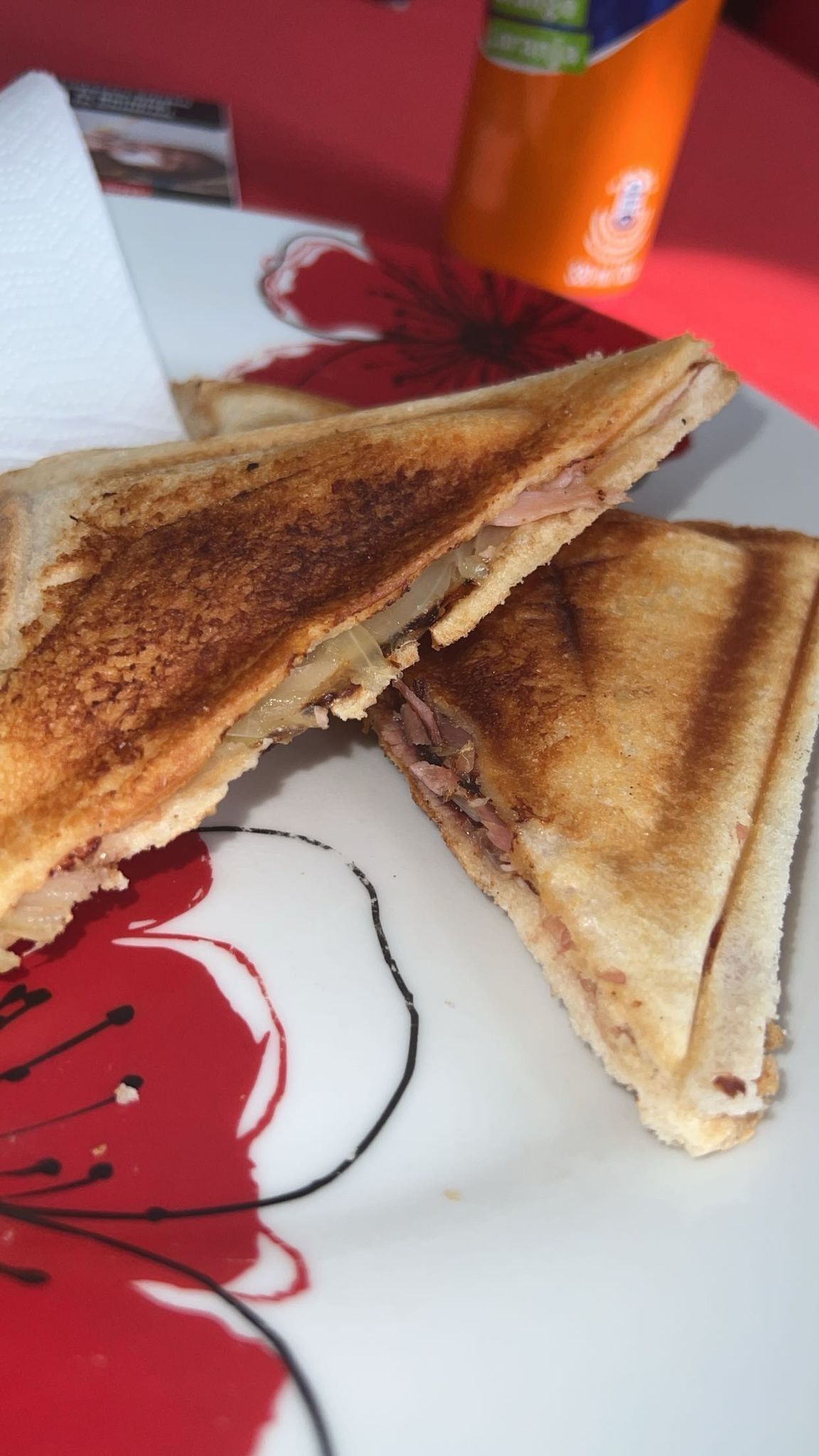 A sandwich cut in half on a plate with a red and white design.