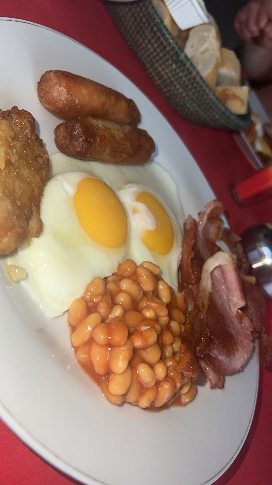 Un plato con huevos, salchichas, frijoles y tocino.