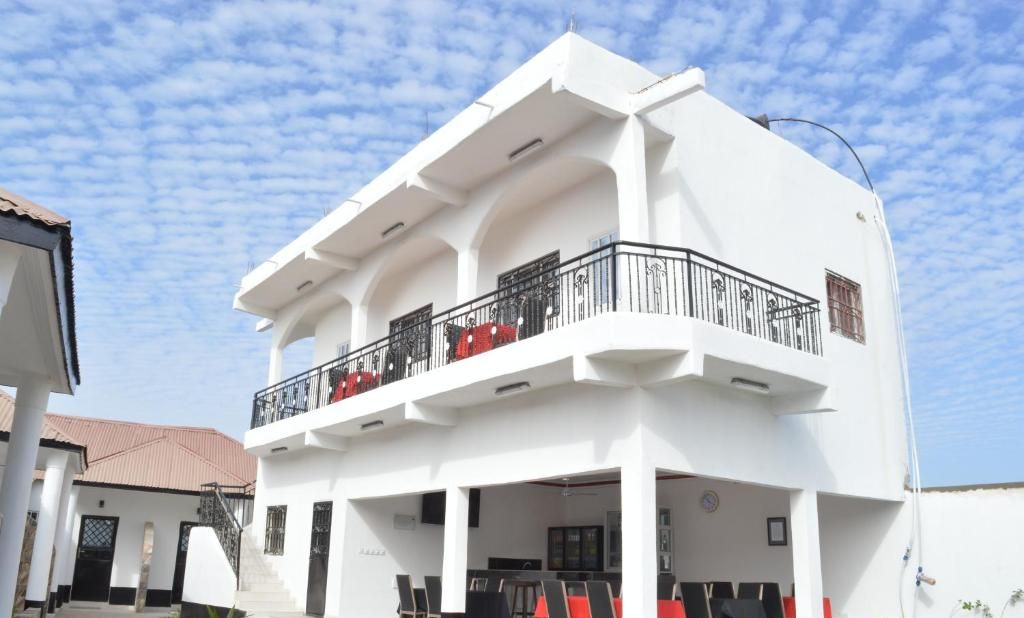 A two-story building with a balcony, outdoor seating area, and a staircase leading to the entrance.