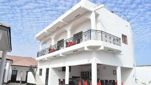 A two-story building with a balcony, outdoor seating area, and a staircase leading to the entrance. - Sukuta Nema Guest House (Sukuta)