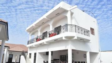 A two-story building with a balcony, outdoor seating area, and a staircase leading to the entrance.