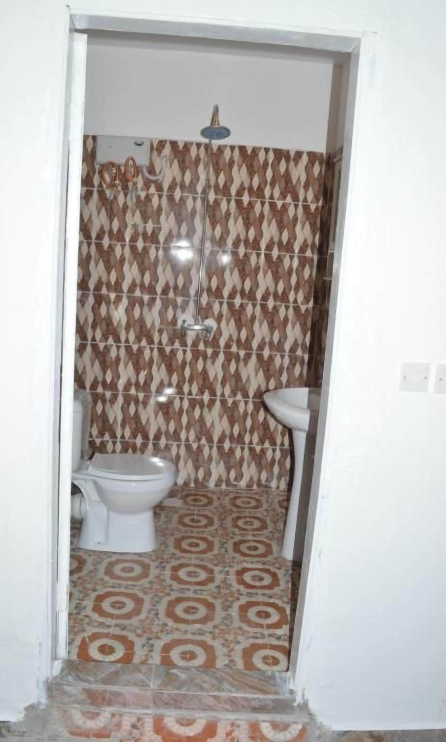 A small bathroom with a shower, toilet, and sink.