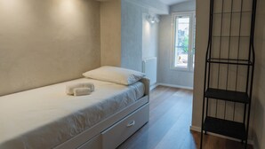 A bedroom with a single bed, a radiator, a window, and a metal shelf unit. - Beachfront apartment in San Giovanni li Cuti suitable for families (Catania)