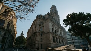 Um edifício histórico com arquitetura clássica, uma torre do relógio e uma rua de paralelepípedos.