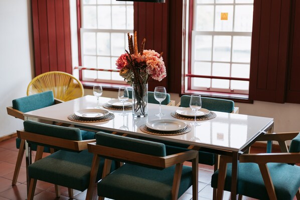 A dining table set with plates, glasses, and a vase of flowers.