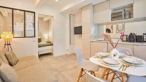 A modern kitchen with a microwave, a coffee machine, and a dining area with a table set for two. - Charming Apartment Center of Paris Le Marais (Paris)