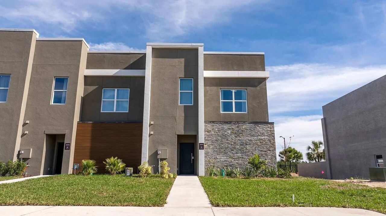 A modern multi-story building with a flat roof, large windows, and a stone facade.