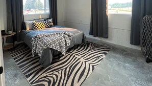 A bedroom with a bed, zebra-patterned rug, and a window with curtains. - Lovely 2-bedroom apartment with mountain views in Anaconda (Anaconda)