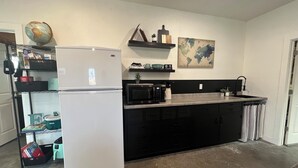 A compact kitchen with a white refrigerator, a microwave, and a small island counter. There is a shelf with books and a globe, and a world map on the wall. - Lovely 2-bedroom apartment with mountain views in Anaconda (Anaconda)