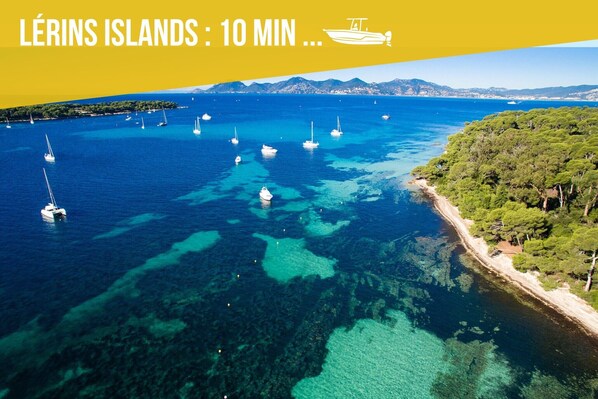An aerial view of the Lérins Islands with clear blue waters, boats, and a coastline with dense greenery.