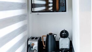 A kitchen with a built-in coffee maker, toaster, and kettle on a countertop.