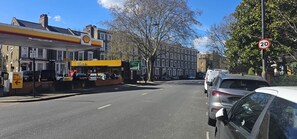 A street with parked cars, a Shell gas station, and a speed limit sign.