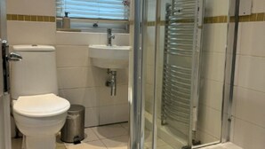 A bathroom with a toilet, sink, and glass-enclosed shower.