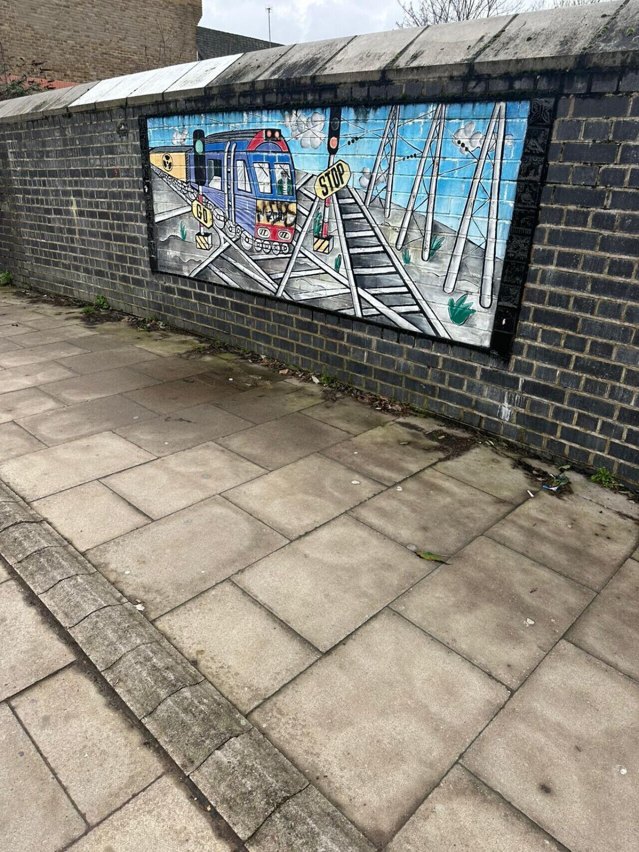 Et mural maleri af et tog på en bro med et stopskilt.