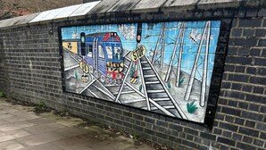 A mural of a train on a bridge with a stop sign.