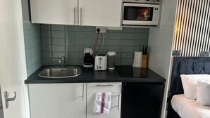 A compact kitchenette with a sink, microwave, toaster, and cabinets.