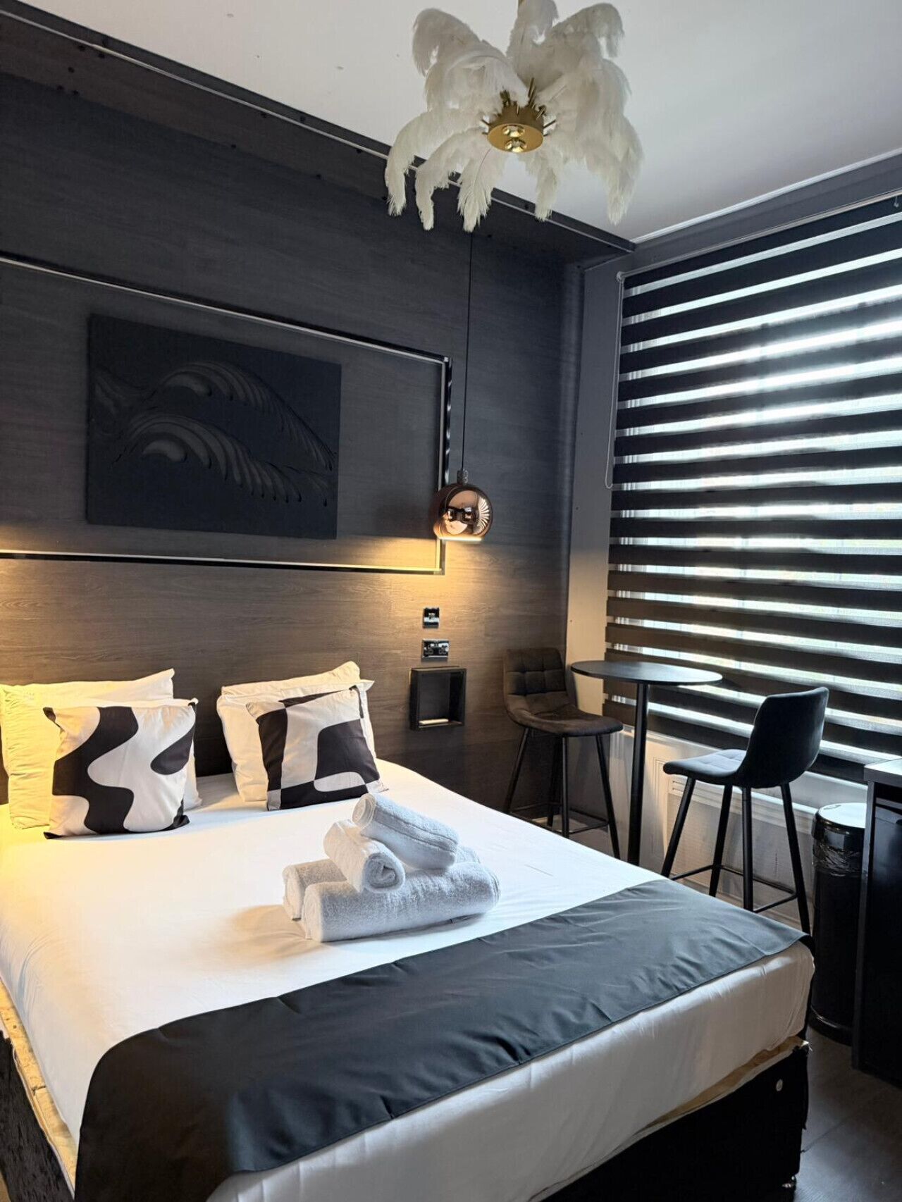 A modern hotel room with a large bed, a desk, and a chair.