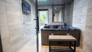 A modern bathroom with a hot tub, marble walls, and a wooden floor. - Fairbridge 2. (Central London)