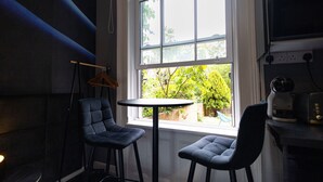 A room with a window, two chairs, a small table, and a hanging rack. - Fairbridge 2. (Central London)
