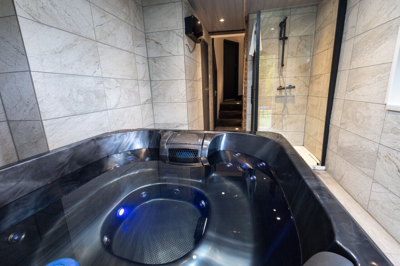 A modern bathroom with a large, curved bathtub, a glass-enclosed shower area, and a marble-tiled floor.