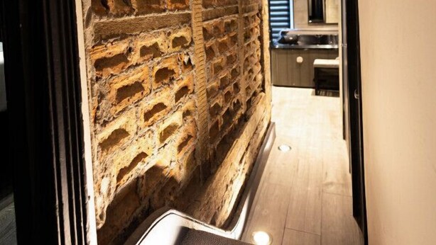 A narrow hallway with exposed brick walls and a modern kitchen area in the background. - Fairbridge 2. (Central London)