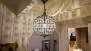 Une pièce dotée d’un grand lustre en cristal, d’un lit avec du linge de lit rose, d’un miroir et d’une coiffeuse en bois.
