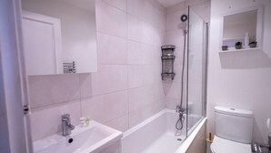 A modern bathroom with a bathtub, a shower, a toilet, and a sink.